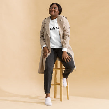 Seating woman in blazer wearing white Merci sweatshirt